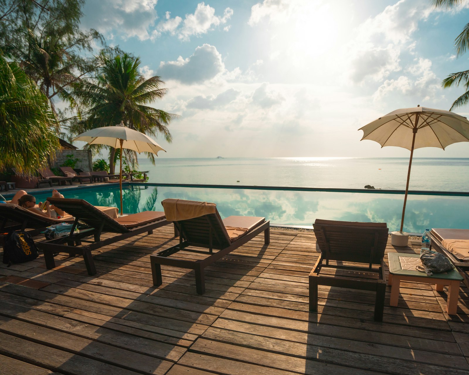 Loungers under a palm-shaded beach umbrella